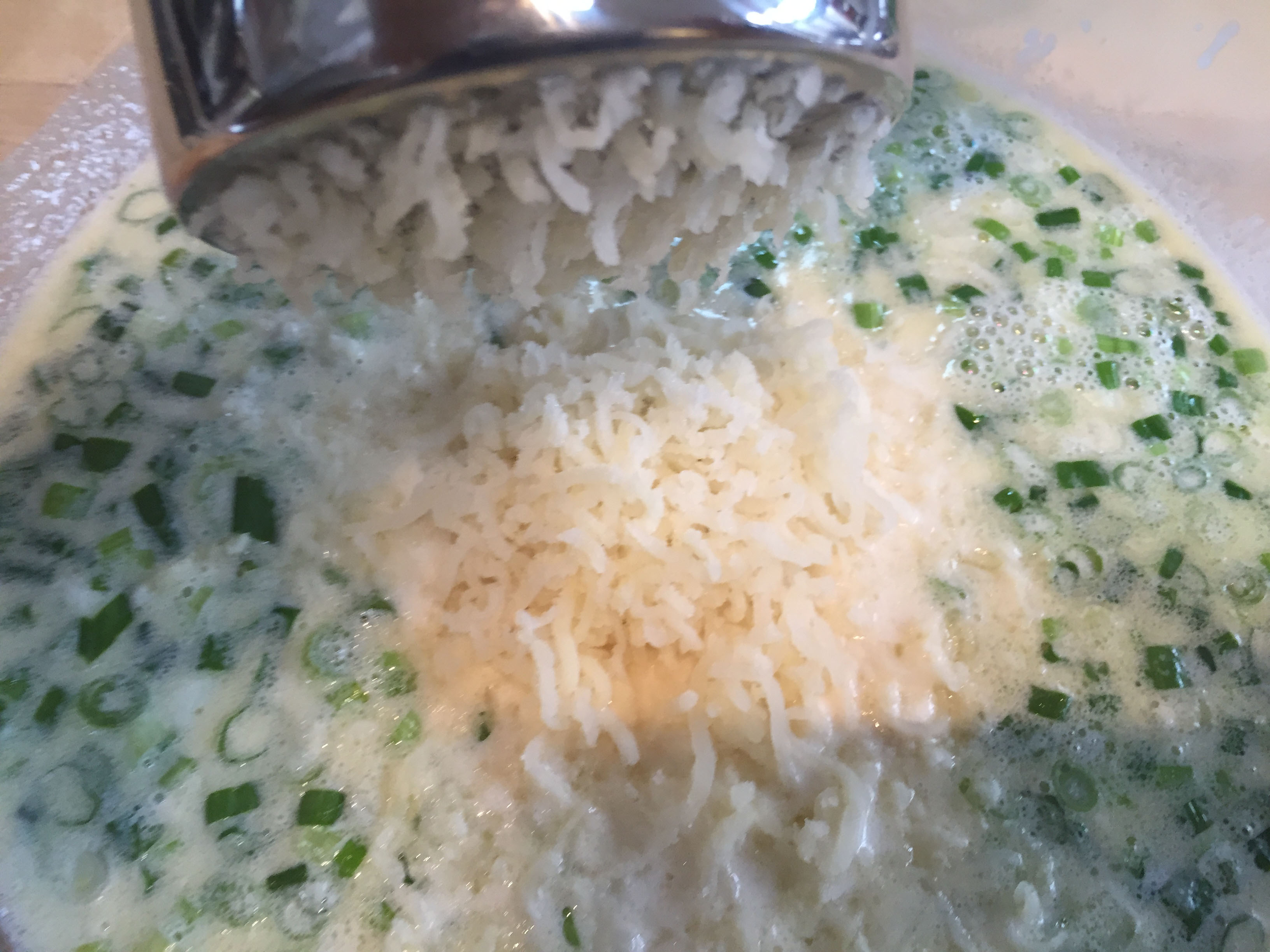 Ricing potatoes into milk and green onions