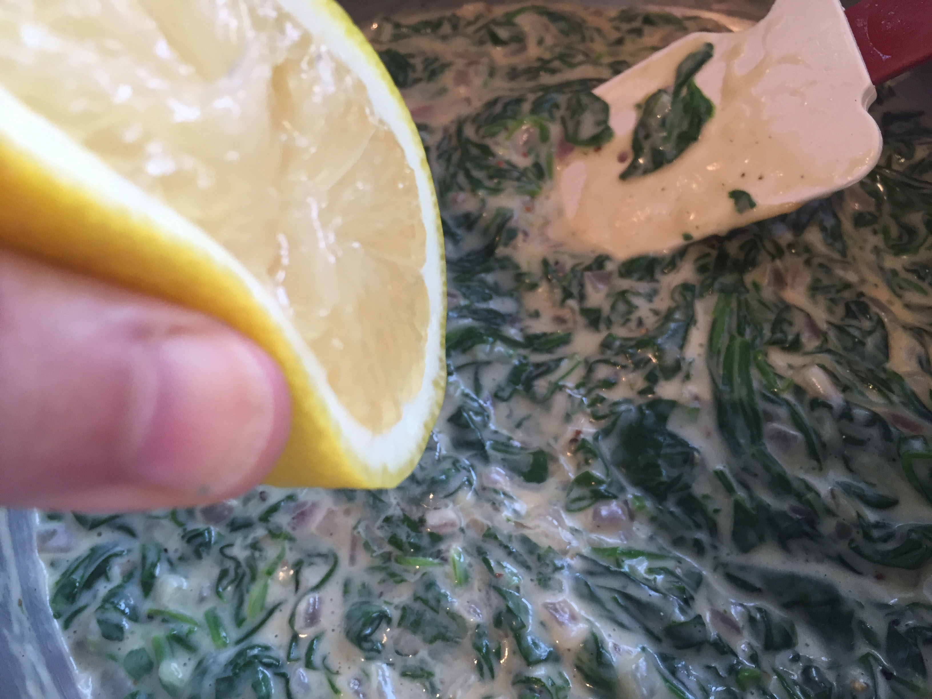 squeezing fresh lemon into creamed spinach